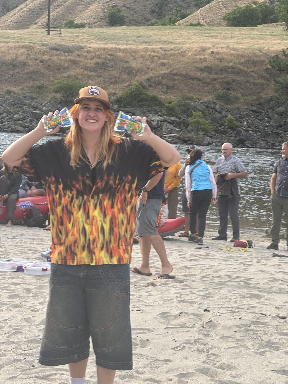 A friend in a flame shirt on the beach, arms raised, the crowd gathered behind