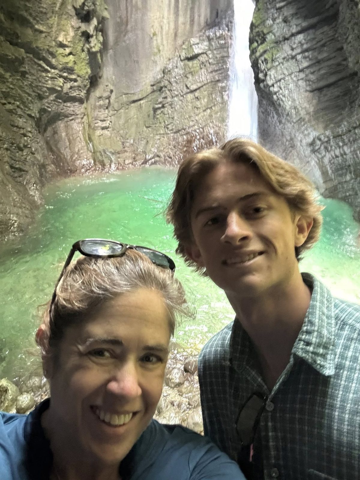 Scott and his mom Stephanie in front of a waterfall and turquoise pool, both smiling