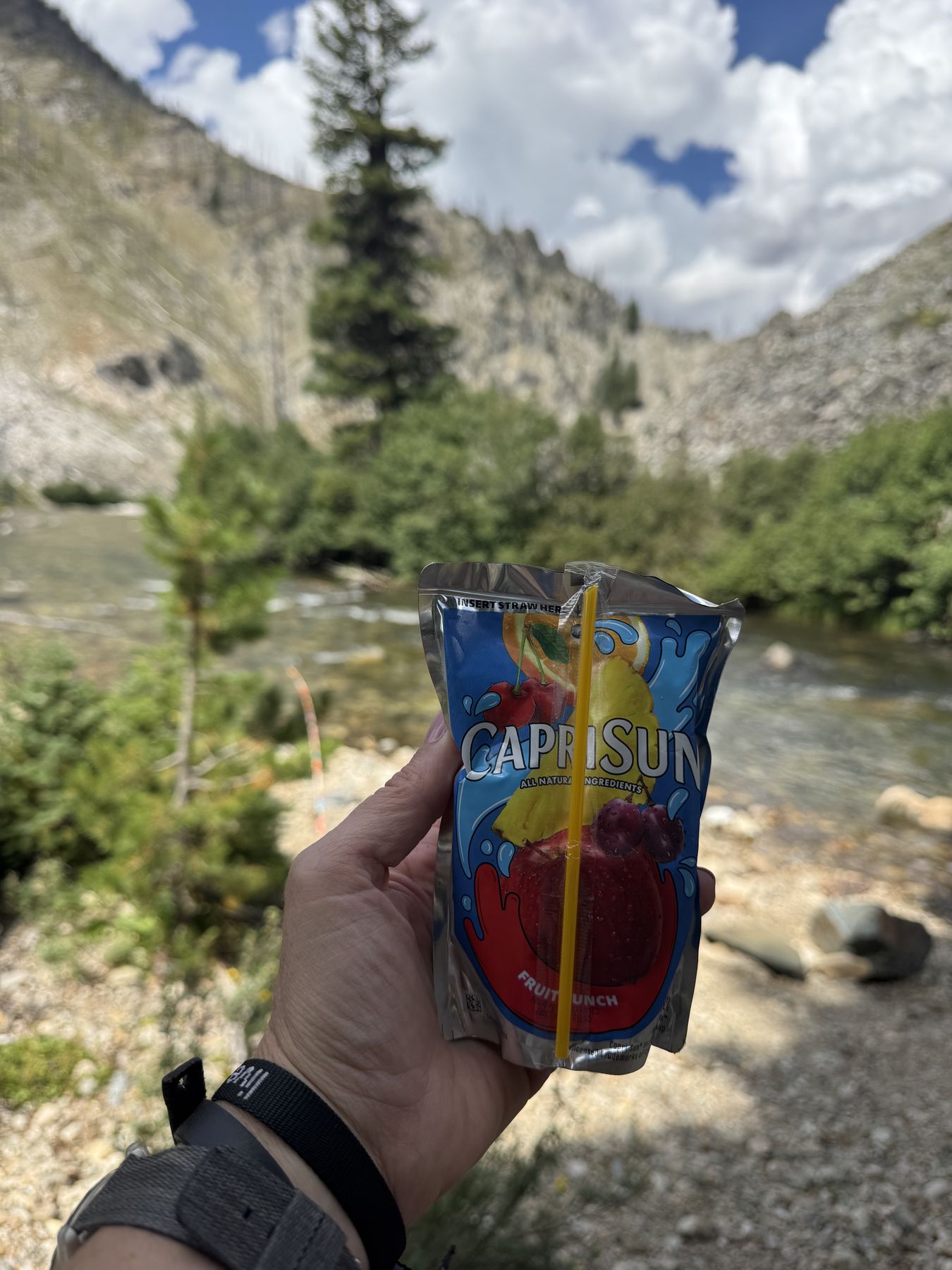 A Capri Sun held up toward Marsh Creek and the canyon walls