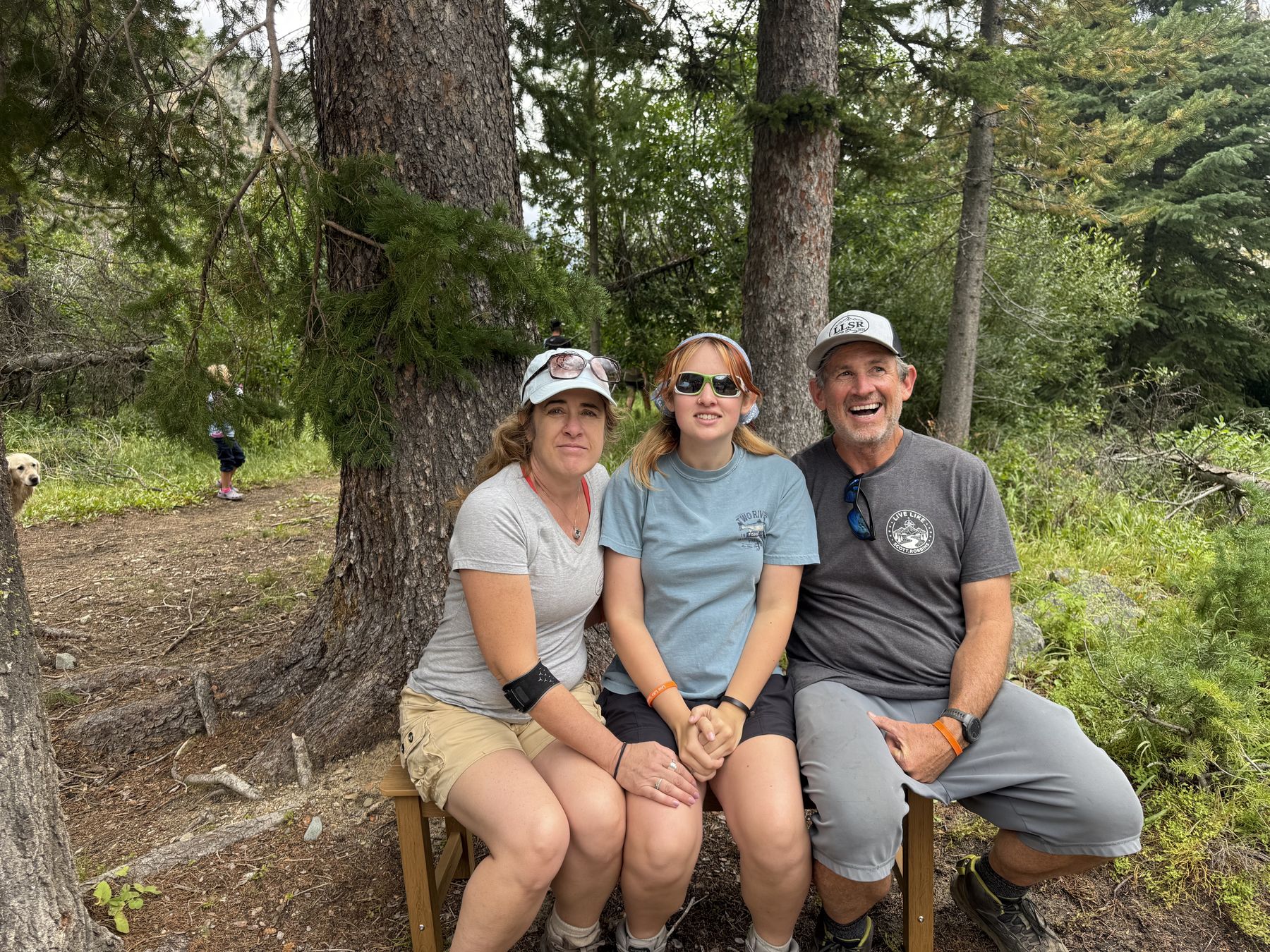 Three of them sitting shoulder to shoulder on Scott&rsquo;s bench in Live Like Scott hats