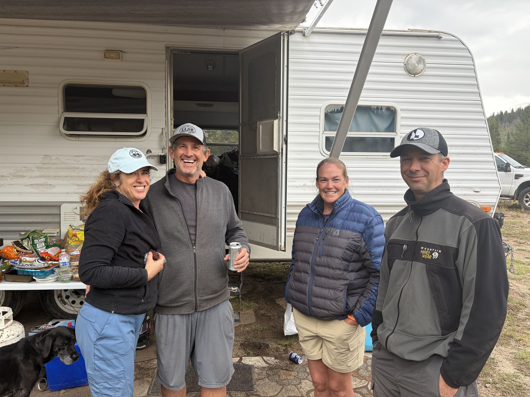 Back at camp &mdash; two couples outside the trailer, food laid out on the table