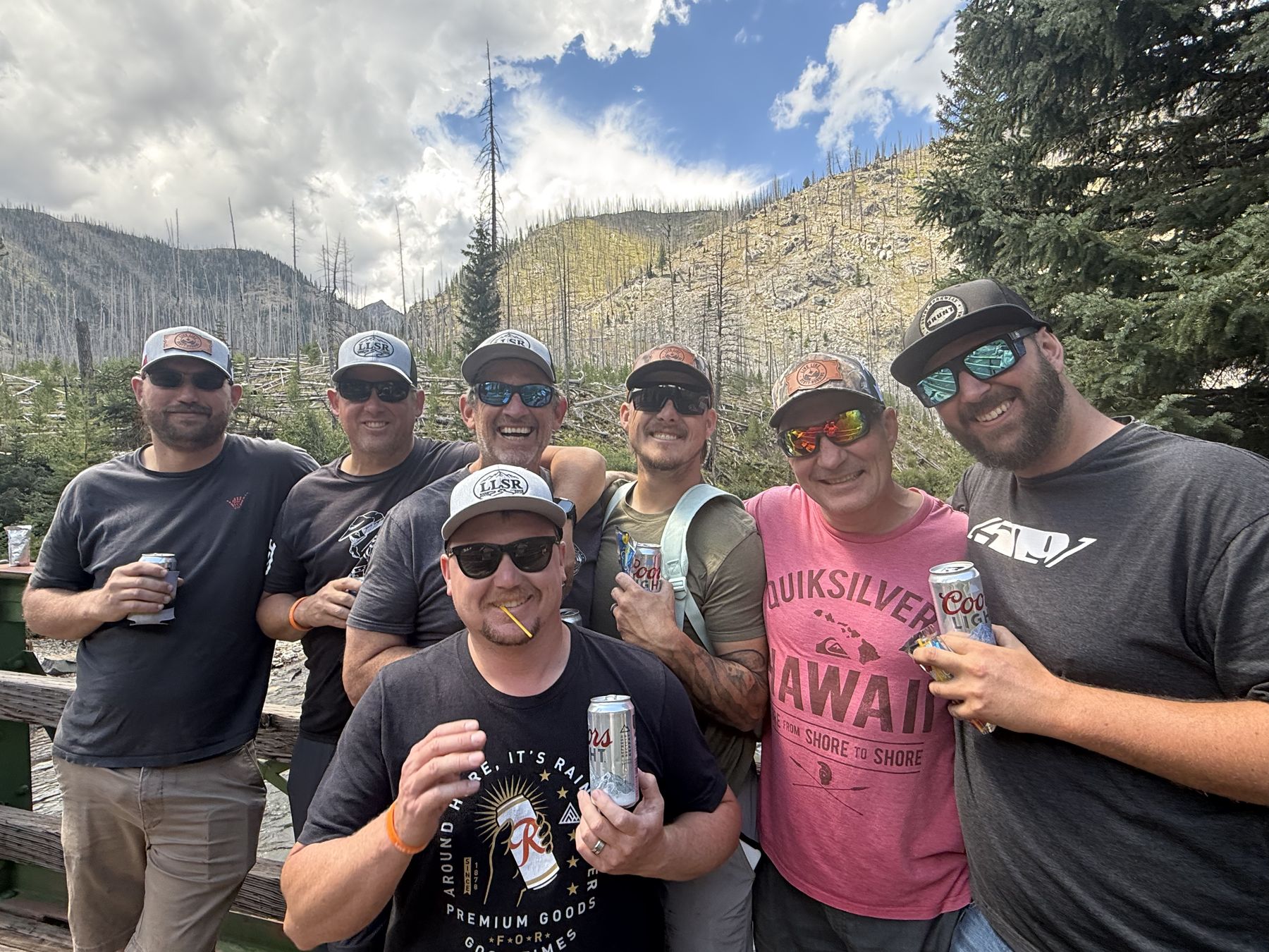 Scott&rsquo;s crew crowded in for a photo in Live Like Scott hats, cans raised, burned ridgeline behind them